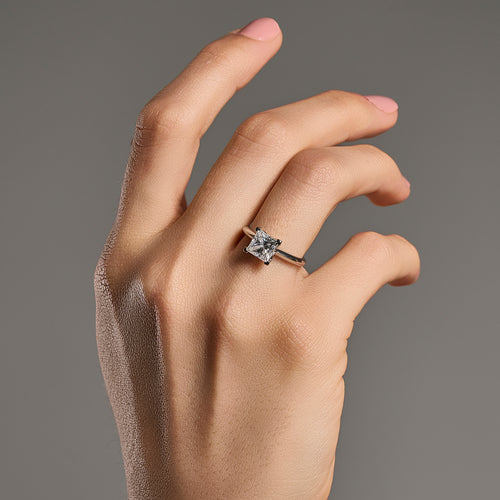 Princess cut moissanite ring with 2 ct center stone worn on hand in 925 sterling silver