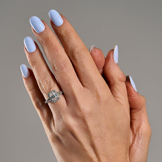 Woman wearing emerald cut moissanite ring with halo design in 925 sterling silver