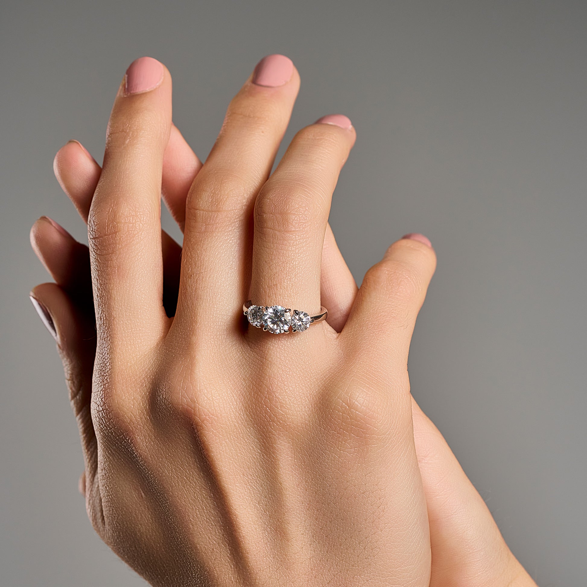 Woman wearing trilogy ring with 2.2 ct brilliant cut moissanite in 925 sterling silver