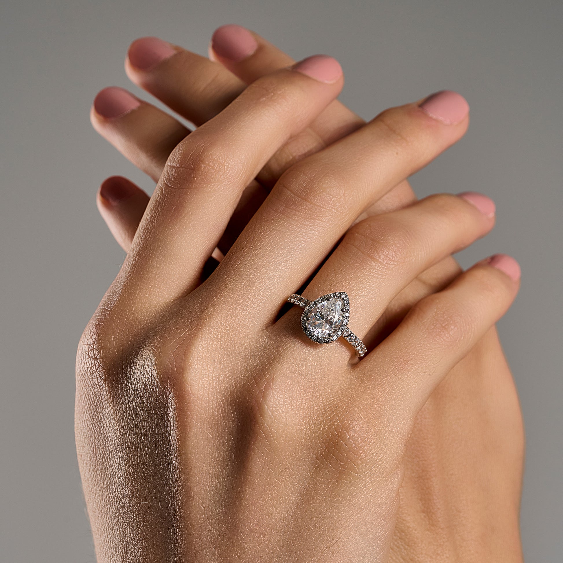 Woman wearing pear cut 2 ct moissanite halo ring in 925 sterling silver