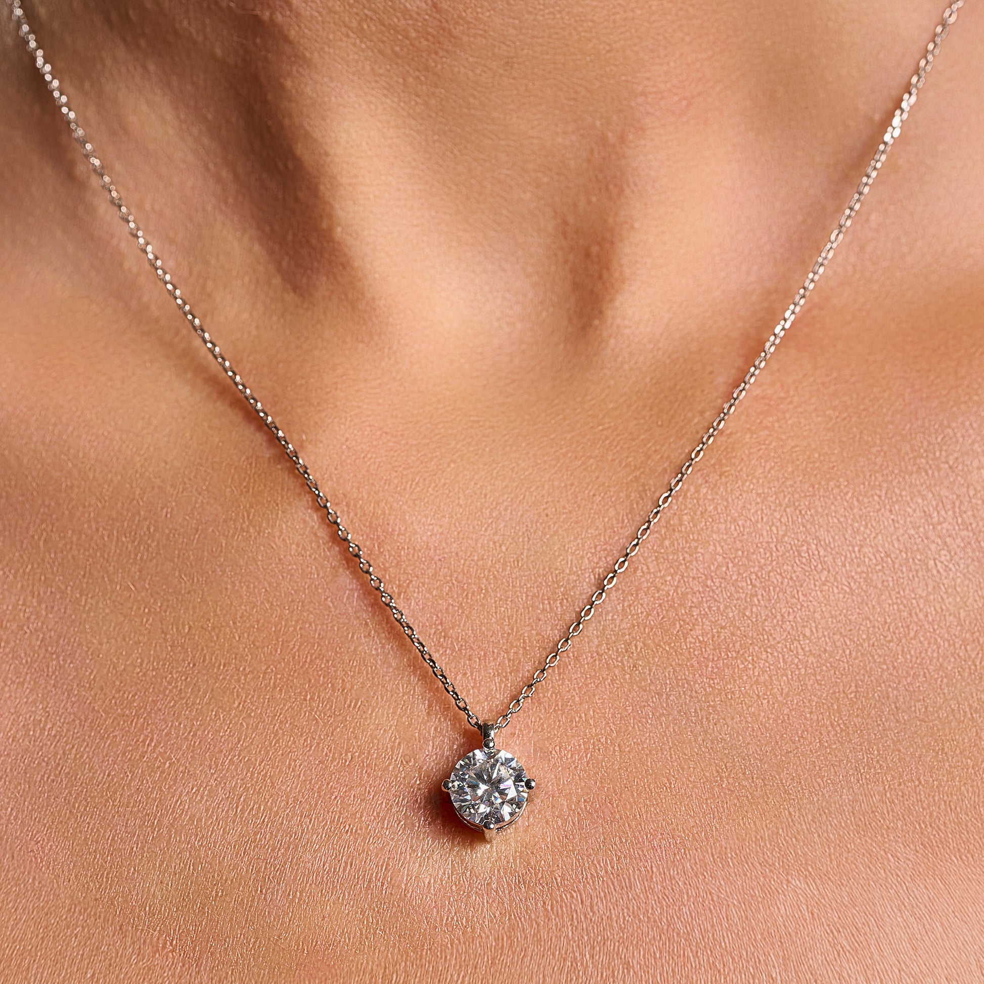 Close-up lifestyle image of a woman wearing a Light Point necklace with 2 ct round brilliant cut moissanite in 925 sterling silver.
