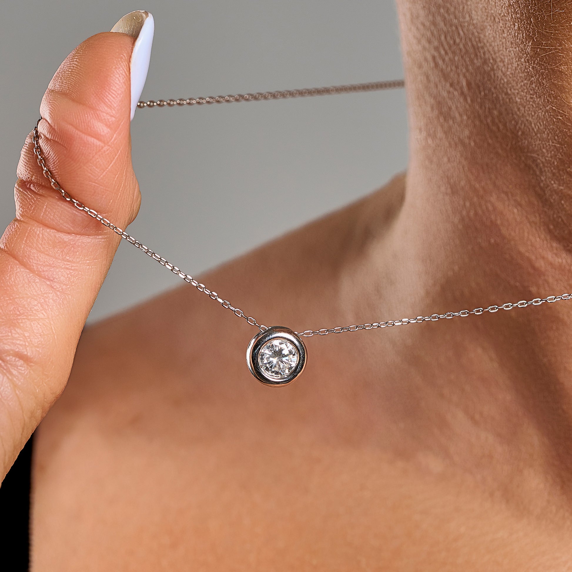 Close-up of a model wearing a light point necklace in 925 sterling silver with 1 ct brilliant cut moissanite and silver contour.