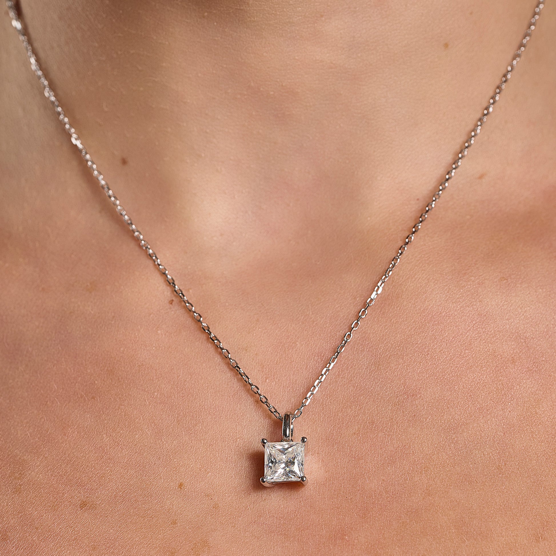Model wearing a 925 sterling silver necklace with a 2 ct princess cut moissanite pendant on a minimalist neckline.