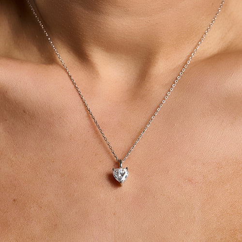 Model wearing a 925 sterling silver necklace with a 2 ct heart cut moissanite pendant in a minimalist neckline close-up.