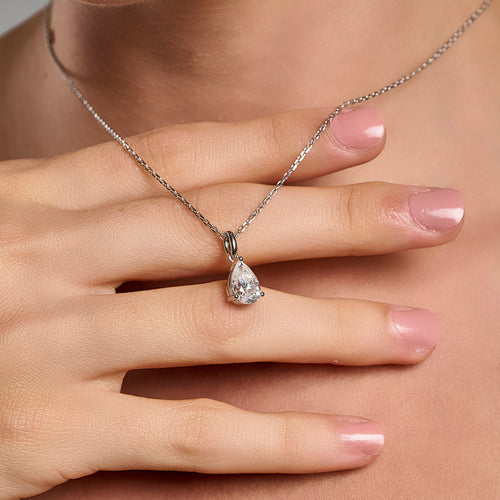 Model wearing a 925 sterling silver necklace with a 1 ct pear cut moissanite pendant, shown in a close-up hand styling shot.
