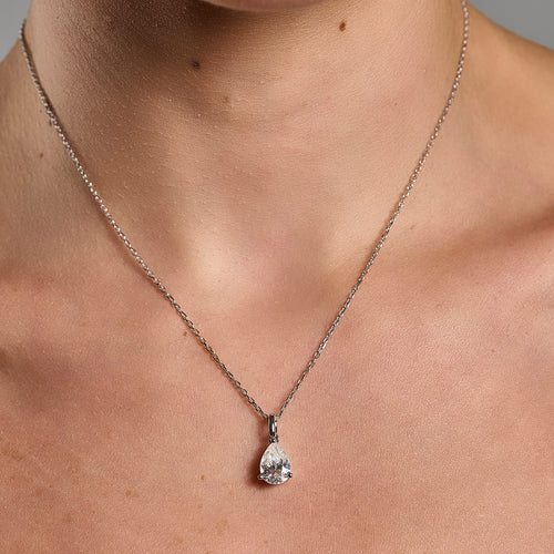 Model wearing a 925 sterling silver necklace with a 1 ct pear cut moissanite pendant in a minimalist neckline close-up.