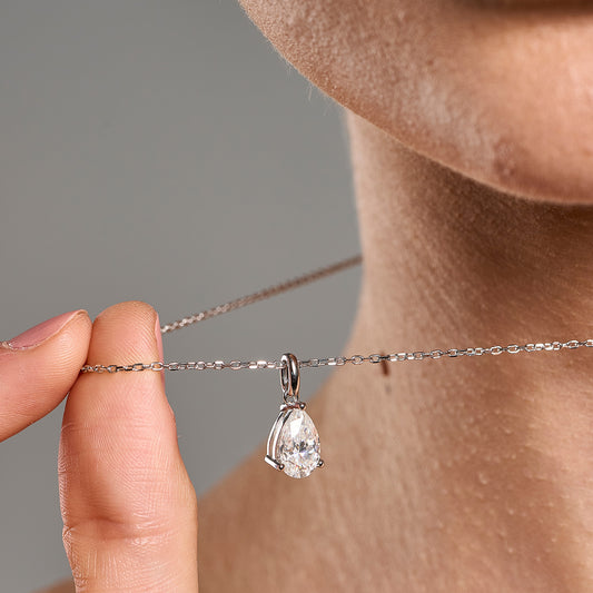 Model wearing a 925 sterling silver necklace with a 2 ct pear cut moissanite pendant, shown in a close-up styling shot.