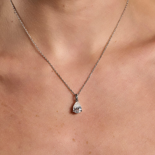 Model wearing a 925 sterling silver necklace with a 2 ct pear cut moissanite pendant in a minimalist neckline close-up.