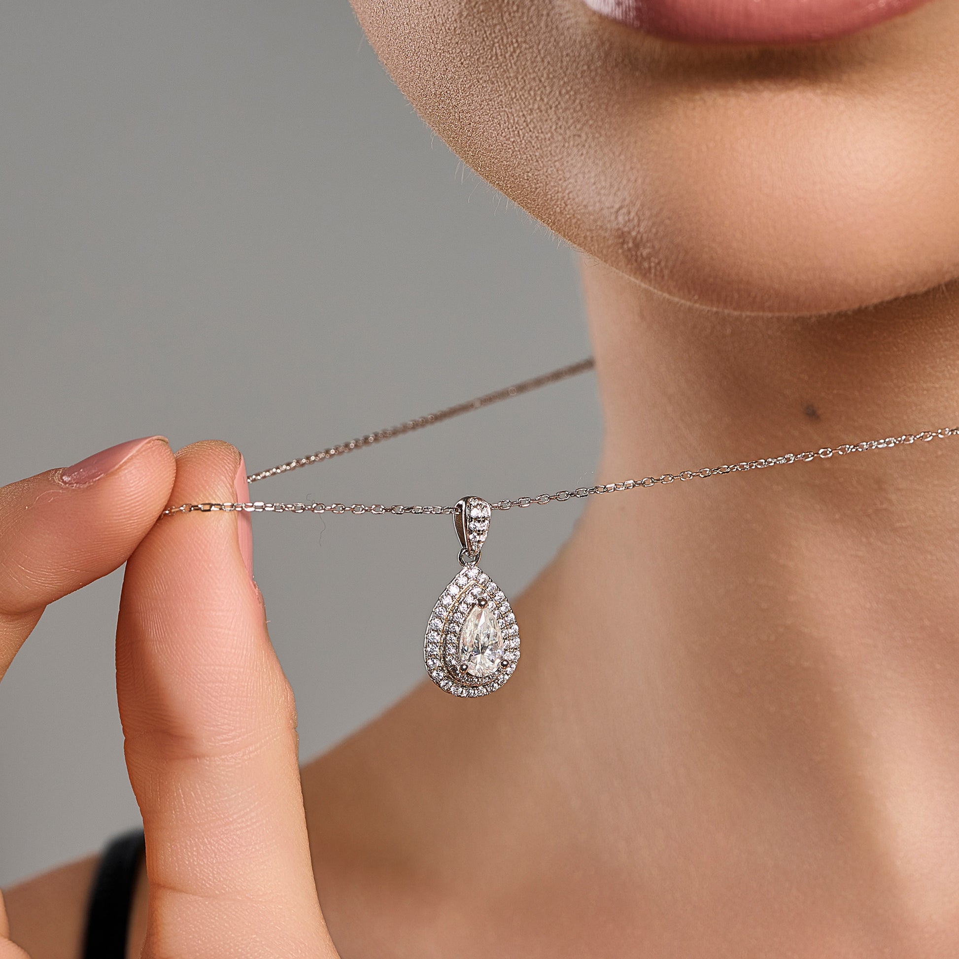 Goccia Contorno -teardrop halo- necklace in 925 sterling silver with 1 ct moissanite held near the neck