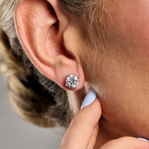 Woman wearing 2 ct brilliant cut moissanite stud earrings in 925 sterling silver, displaying luxurious sparkle and elegant everyday style.