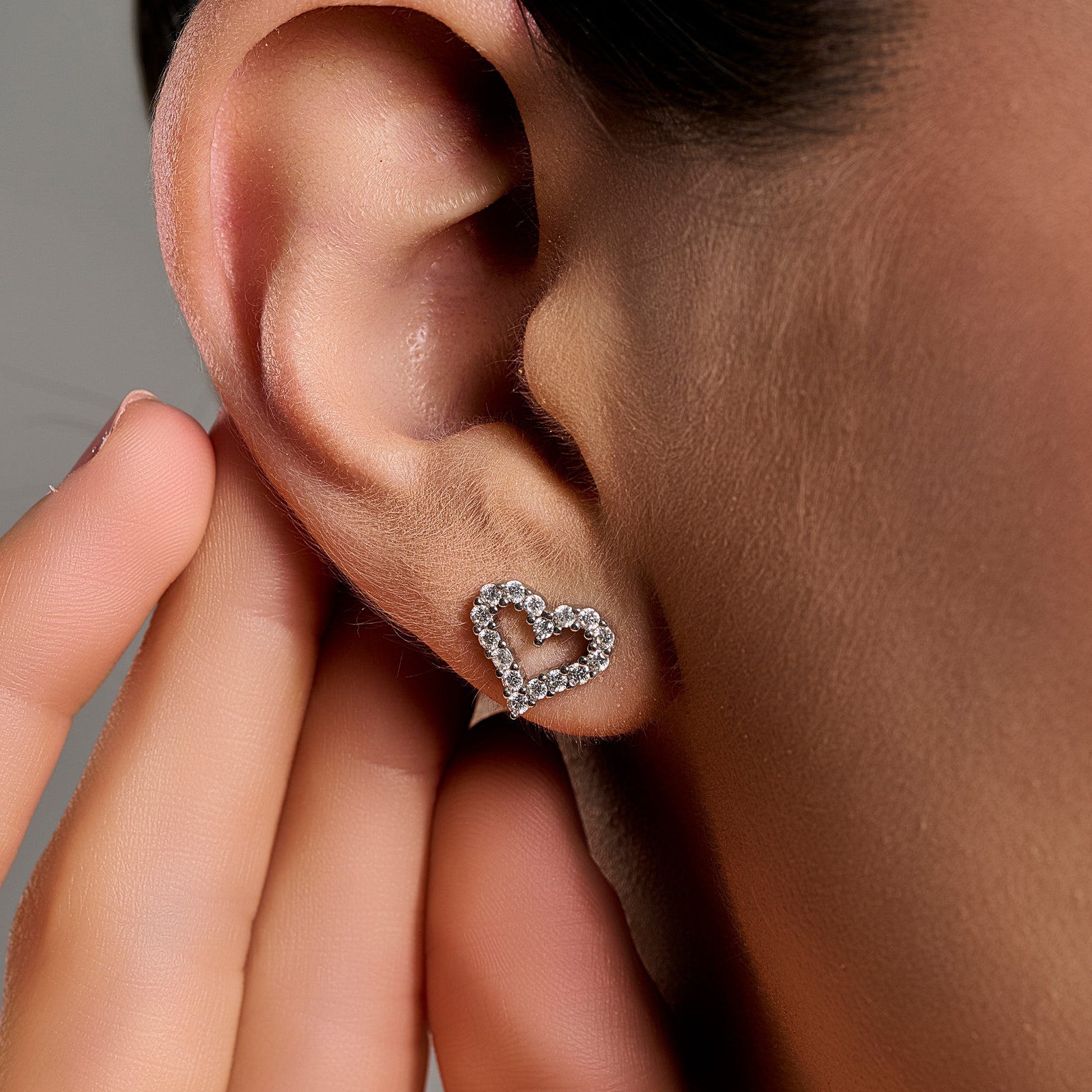 Woman wearing heart-shaped moissanite earrings in 925 sterling silver, showcasing a romantic open-heart design with brilliant sparkle.