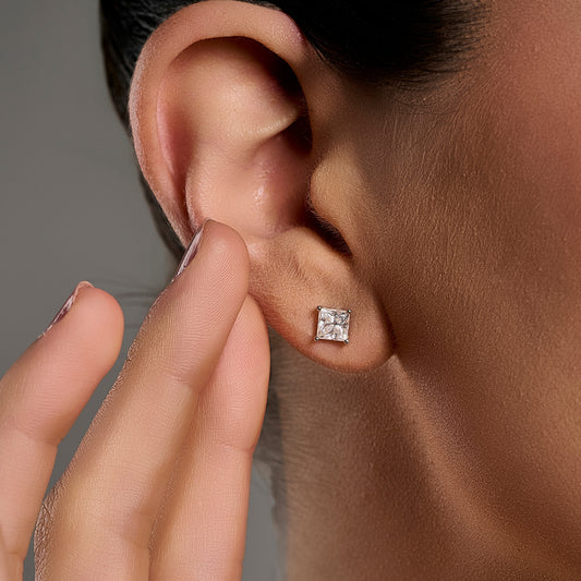 Princess cut moissanite stud earring in 925 sterling silver worn on the model’s ear.
