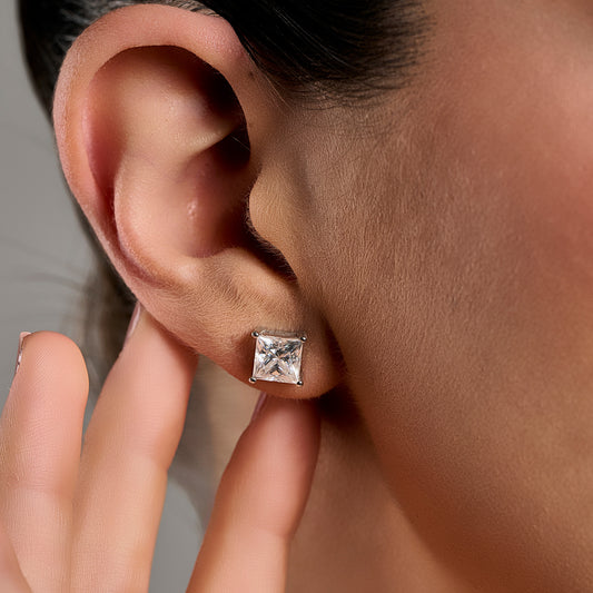 Princess cut moissanite stud earring in 925 sterling silver worn on the model’s ear.