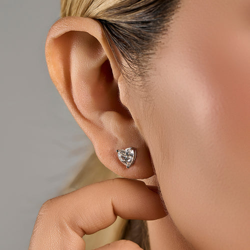 Heart cut moissanite stud earring in 925 sterling silver worn on the model’s ear.