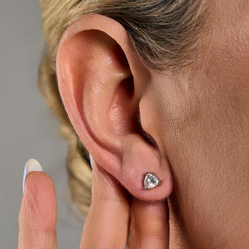 Trillion cut moissanite stud earring in 925 sterling silver worn on the model’s ear.