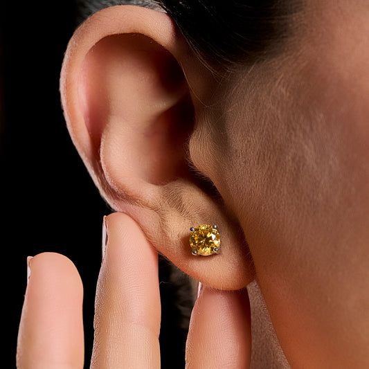 Close-up lifestyle image of a woman wearing a Summer Edition round yellow earring featuring a 1 ct brilliant cut yellow moissanite set in 925 sterling silver.