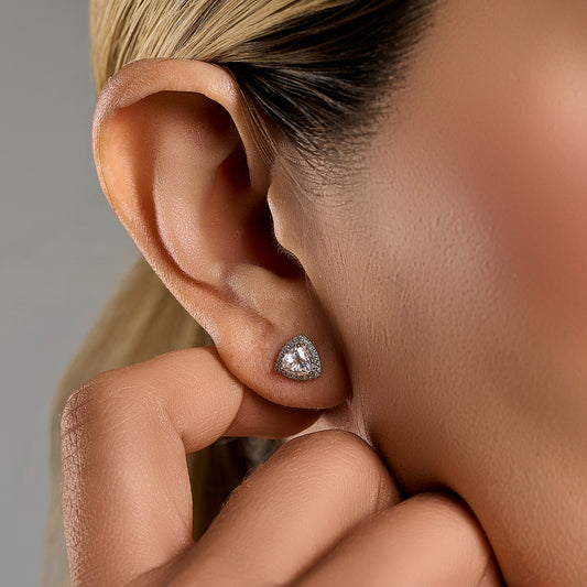 Close-up lifestyle image of a woman wearing trillion cut halo earrings with 1 ct moissanite stones in 925 sterling silver.